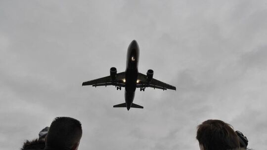 Ein Flugzeug über den Köpfen einer Familie