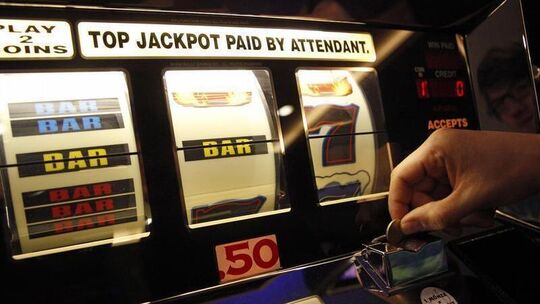 Hand wirft Münze in Spielautomaten