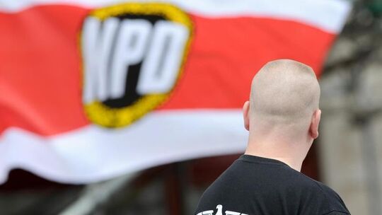Mann steht vor NPD-Fahne