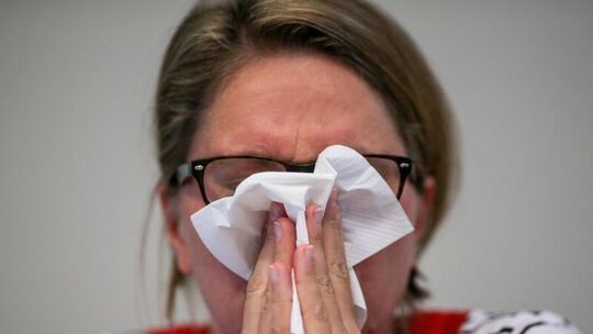Eine Frau putzt sich die Nase