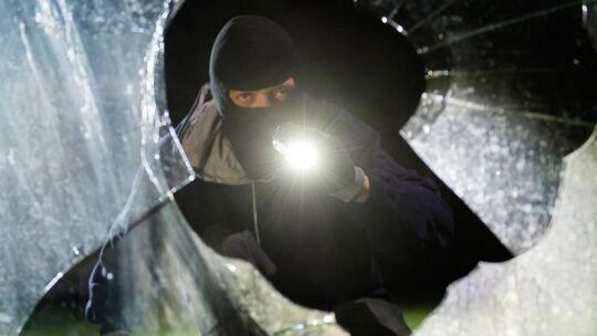 Einbrecher schlägt eine Scheibe ein