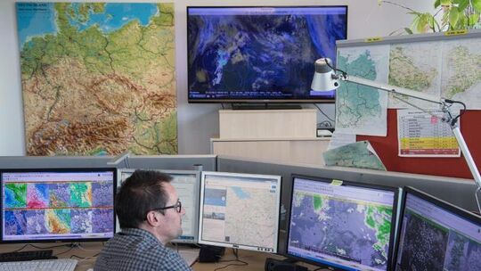 Ein Mann sitzt vor Computerbildschirmen mit Wetterdaten