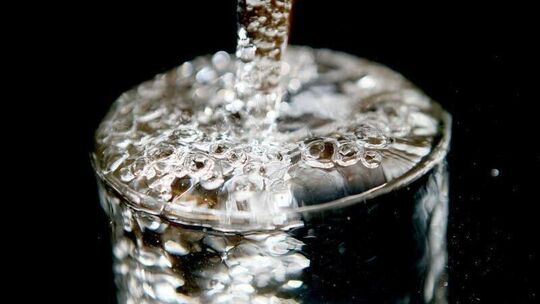 Ein Wasserglas läuft voll mit Trinkwasser