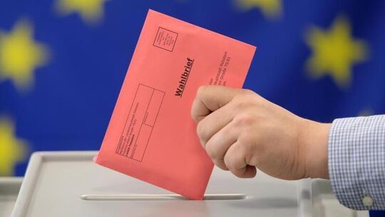 Ein Wahlbrief wird in eine Wahlurne gesteckt