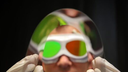 Mitarbeiter hält biegsame, ultradünne Glasscheibe vor die Kamera