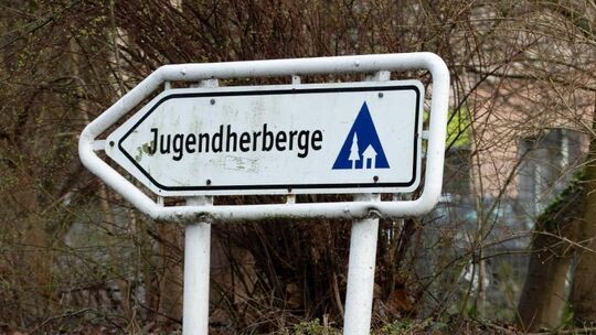 Blick auf einen Wegweiser vor einer Jugendherberge