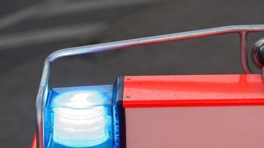 Ein Fahrzeug der Feuerwehr fährt mit Blaulicht über eine Straße