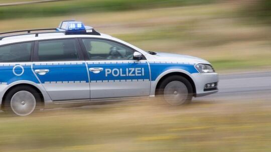 Ein Polizeifahrzeug fährt mit Blaulicht auf der Landstraße