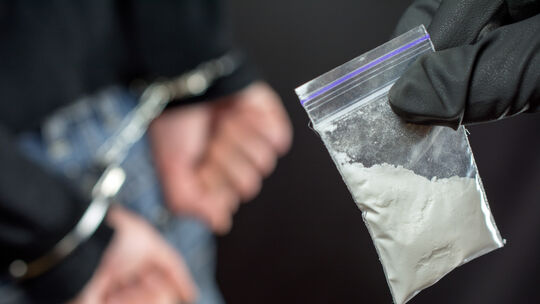 Police arrest drug trafficker with handcuffs. police officer finds A Little Bag Of Drugs during the search of drug dealer