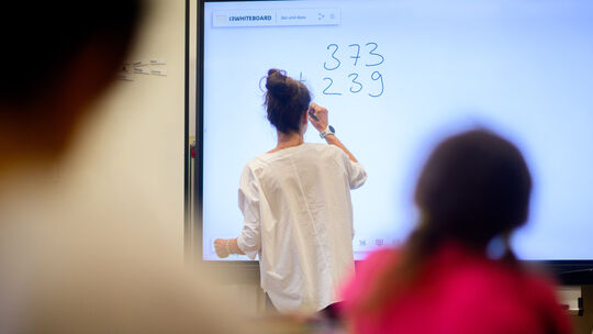 Eine Lehrerin schreibt eine Mathematikaufgabe auf eine digitale Schultafel im Klassenraum einer 4. Klasse einer Grundschule. (zu Mehr Quereinsteiger an Niedersachsens Schulen