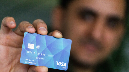 Ein Geflüchteter hält eine Debitcard in der Hand. Der Ortenaukreis zwischen Rhein und Schwarzwald will von diesem Dienstag an di Neue Bezahlkarte für Geflüchtete