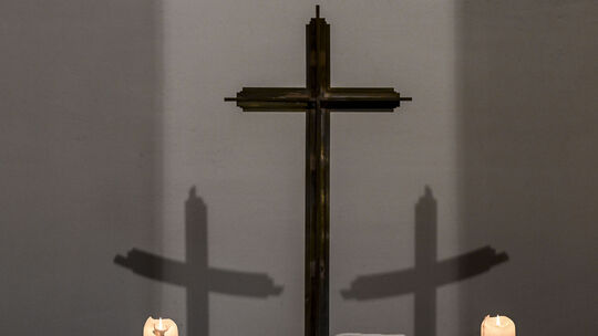 Brennende Kerzen und Kreuz