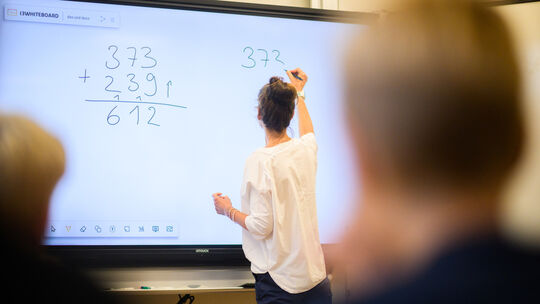 Eine Lehrerin schreibt eine Mathematikaufgabe auf eine digitale Schultafel im Klassenraum einer 4. Klasse einer Grundschule in d Lehrkräfte in Niedersachsen