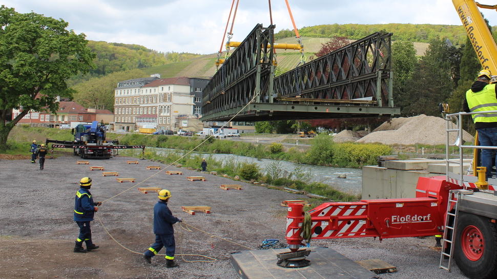 Mit einem Baukran wird die Behelfsbrücke aus der Verankerung gehoben.