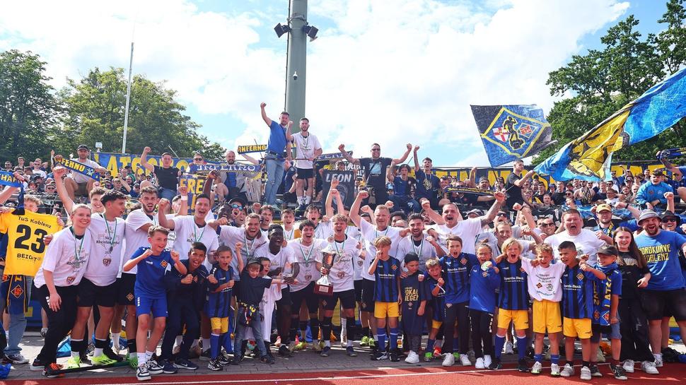 Gruppenbild mit Pokal und Fans: Die TuS-Spieler feiern ausgelassen zusammen mit den Anhängern den Gewinn des Pokals.