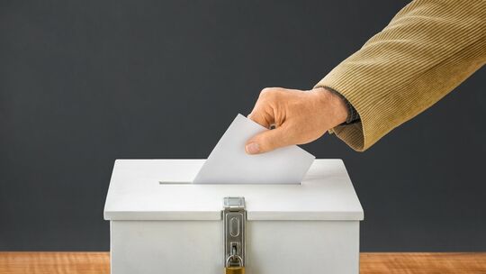 Mann wirft Stimmzettel in Wahlurne