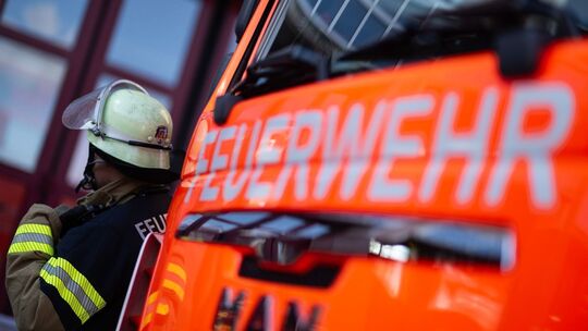 Feuerwehrmann steht neben einem Feuerwehrauto (Symbolbild)