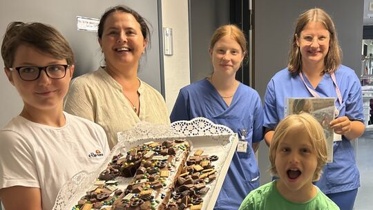 Ein Jahr nach seiner Lebenrettung bringen Konrad (vorn) und seine Familie Kuchen und danken dem Team von der Kinderintensivstati