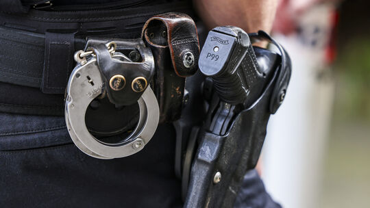 Symbolfoto zu Polizeieinsatz in Boppard: Ein Polizeibeamter trägt seine Dienstwaffe und Handschellen.