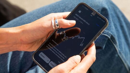 Eine Frau sieht sich einen ETF-Kurs auf einem Handy an
