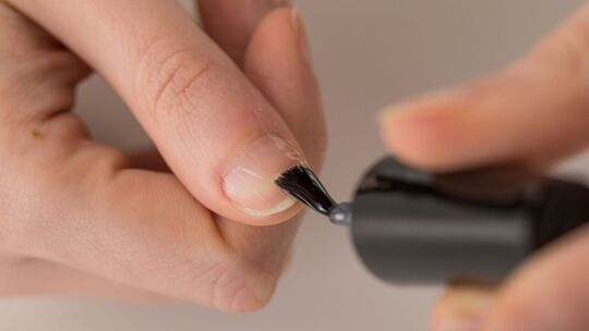 Eine Frau trägt transparenten Nagellack auf
