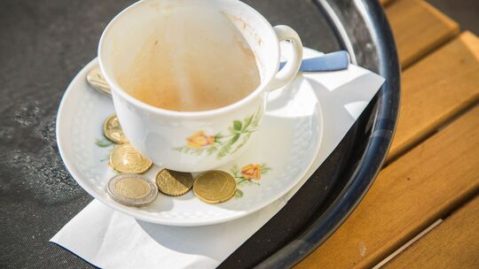 Trinkgeld liegt neben einem Cappuccino auf einem Tablett
