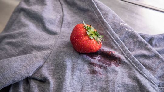 Eine Erdbeere liegt auf einem T-Shirt