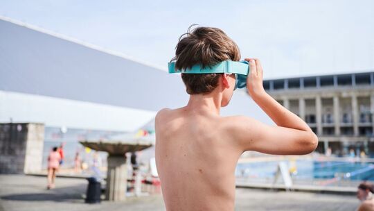 Ein Kind setzt sich seine Schwimmbrille auf