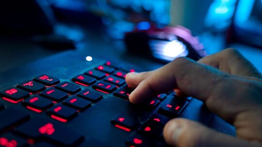 Ein Mann sitzt am Rechner und tippt auf einer Tastatur