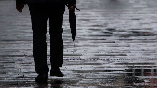 Ein Passant geht mit Regenschirm in der Hand durch Mainz