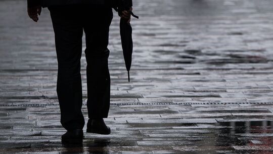 Ein Passant geht mit Regenschirm in der Hand durch Mainz