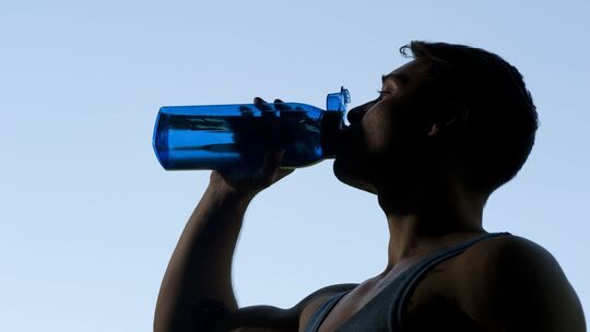 Ein Sportler trinkt aus einer Trinkflasche