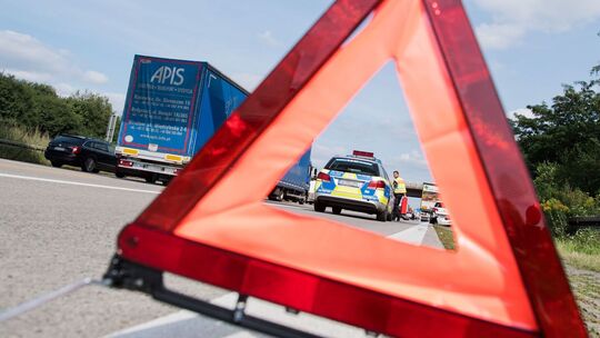 Ein Polizist sichert eine Unfallstelle hinter eihen Warndreieckab