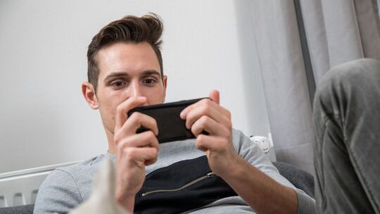 Ein Mann spielt auf seinem Smartphone ein Spiel