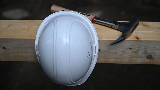 Bauhelm und Zimmermannshammer auf einer Baustelle