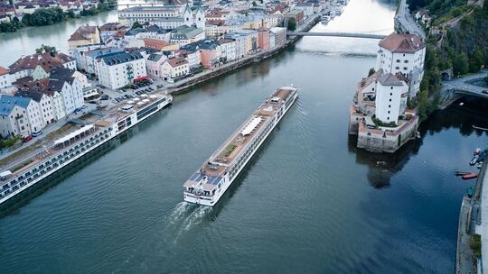 Ein Flusskreuzfahrtschiff fährt stromaufwärts an Passau vorbei