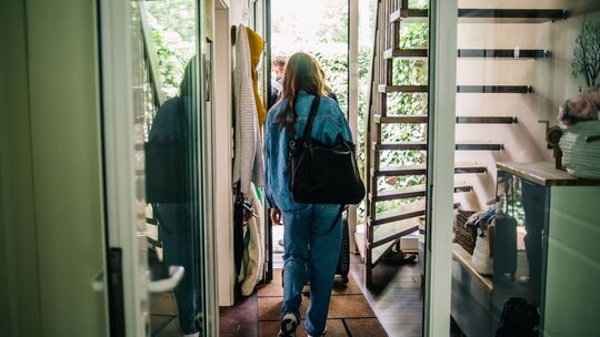 Eine junge Frau verlässt ein Haus