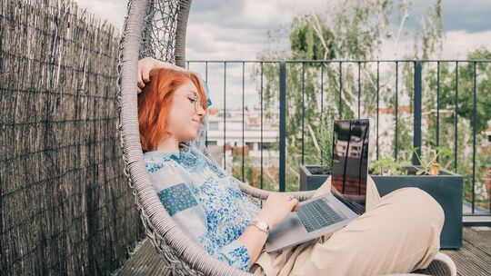 Eine Frau arbeitet auf einer Terrasse im Homeoffice