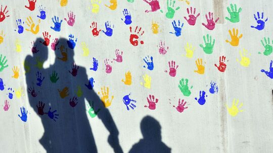 Schatten auf einer Wand mit bunten Handabdrücken