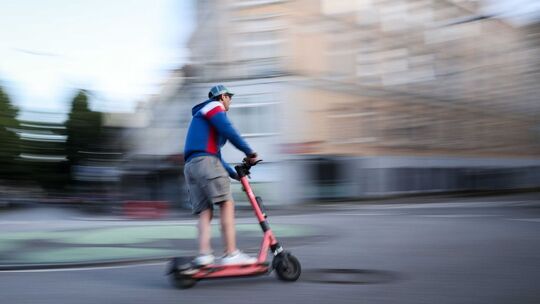Mann fährt mit einem E-Scooter