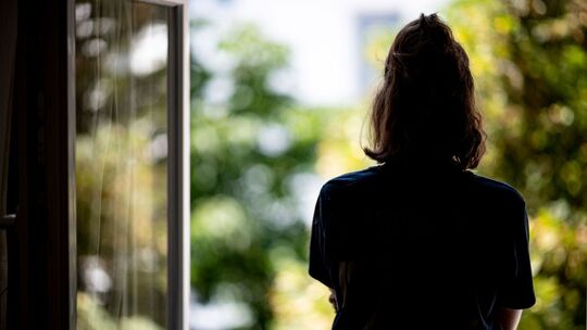 Eine Frau steht an einem offenen Fenster
