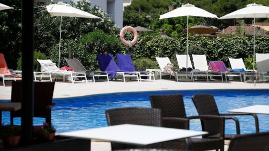 Handtücher liegen auf Sonnenliegen an einem Pool