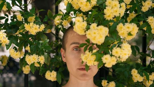 Eine Junge Frau hinter Blumen im Park