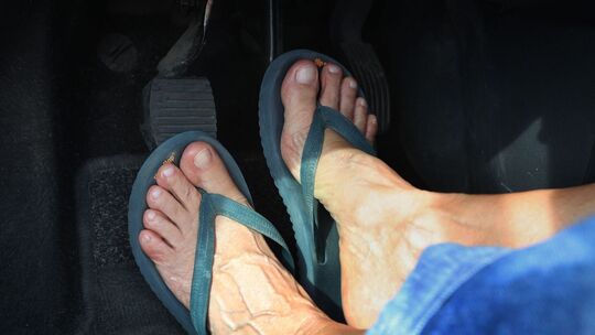 Frau mit Flip-Flops am Steuer eines Autos