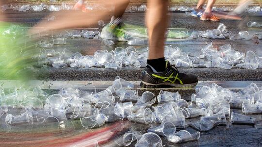 Ein Jogger läuft über benutzte Wasserbecher