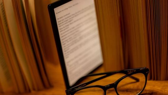 E-Book-Reader steht zwischen Büchern auf einem Tisch