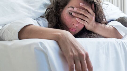 Frau fässt sich verschlafen an den Kopf