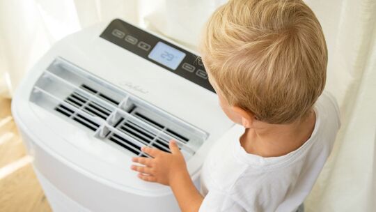 Junge steht vor einer Klimaanlage