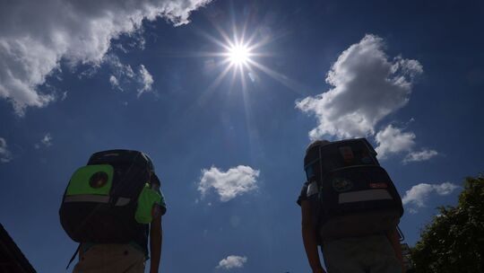 Zwei Schüler mit Ranzen laufen im Sonnenschein