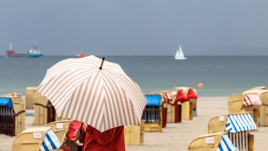 Eine Frau mit Schirm am Strand